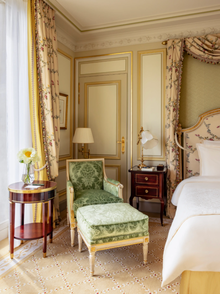 une chambre deluxe au Ritz avec un fauteuil à côté du lit