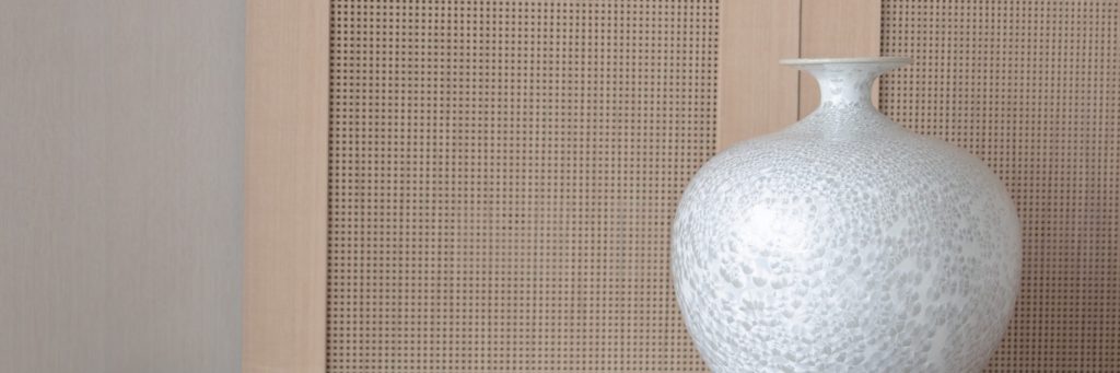 Commode simple et épurée en bois et en verre surplombé d'un vase aux textures uniques.