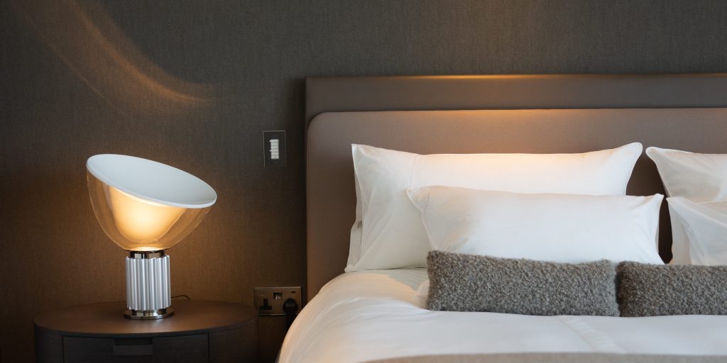 La lampe Taccia de Flos à gauche d'un lit élégant